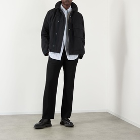 Model wearing Thom Browne Mariner Technical Jacket in black with detachable hood, styled with black trousers and chunky leather shoes.