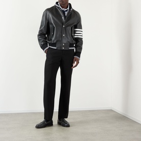 Model wearing Thom Browne 4-Bar Leather Bomber Jacket in black with white stripe ribbed trims, styled with black trousers and loafers