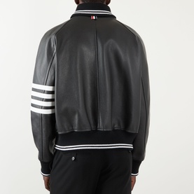 Model wearing Thom Browne 4-Bar Leather Bomber Jacket in black, rear view showing white 4-bar stripe on left sleeve and ribbed trims.