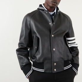 Model wearing Thom Browne 4-Bar Leather Bomber Jacket in black with white ribbed stripe trims, snap buttons, and 4-bar sleeve appliqu&eacute;