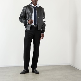 Model wearing Thom Browne 4-Bar Leather Bomber Jacket in black with white ribbed trim and 4-bar stripe at sleeve, styled with black trousers and tie