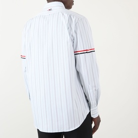 Model wearing Thom Browne medium grey pinstripe cotton shirt, back view, with red, white and blue grosgrain armband detail.