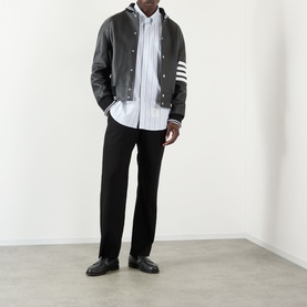 Model wearing Thom Browne Medium Grey casual shirt, styled with a dark varsity jacket, black trousers, and black leather shoes.
