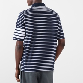 Model wearing Thom Browne navy and white striped cotton polo, rear view showing signature four-bar white stripe detail on left sleeve.