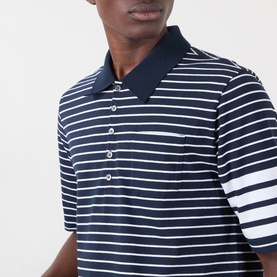 Model wearing Thom Browne navy and white stripe cotton polo shirt with contrast collar and chest pocket, close-up shot.