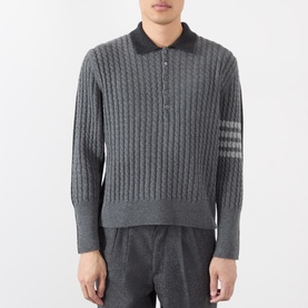 Model wearing Thom Browne Tonal Grey wool cable-knit polo with dark collar, 4-bar stripe detail on sleeve, paired with grey trousers.