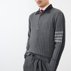 Model wearing Thom Browne Tonal Grey wool cable-knit polo with four-bar stripe sleeves, styled with white shirt, tie and grey trousers.
