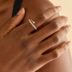 Model with Astrid & Miyu 18ct gold ring featuring a delicate star motif and pav&eacute; diamond-set band on index finger.