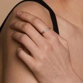Model with Astrid & Miyu gold ring featuring delicate pav&eacute; stone band, worn on finger