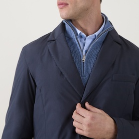 Model wearing Herno Blu Navy down coat, layered over a light blue zip-neck knit and shirt, close-up detail view.
