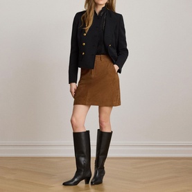 Model wearing Lauren black blazer with gold buttons, styled with tan mini skirt and black knee-high heeled boots