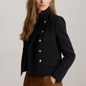 Model wearing Lauren black blazer with gold military-style buttons and high neck, styled with tan trousers
