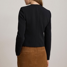 Model wearing Lauren black blazer, rear view, styled with a tan suede mini skirt