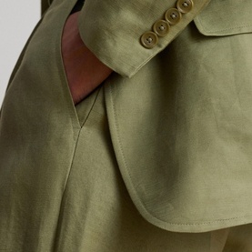 Model wearing Lauren blazer in Light Agave, close-up of hip and pocket detail with brown lining and gold buttons visible.
