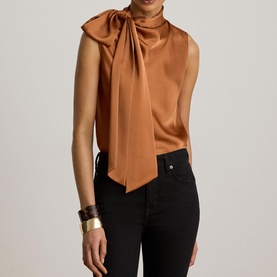 Model wearing Lauren Red Terracotta satin blouse with bow neck tie, styled with black trousers and gold cuff bracelet