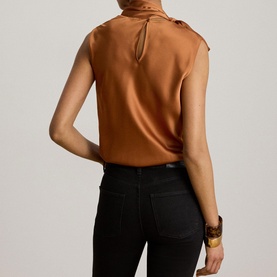 Model wearing Lauren Red Terracotta satin sleeveless blouse with keyhole back detail and mock neck, styled with black jeans and gold cuff bracelet.