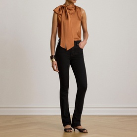 Model wearing Lauren Red Terracotta sleeveless bow-neck blouse, styled with black flared jeans and black flat sandals.