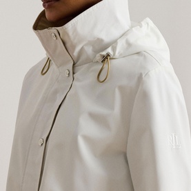 Model wearing Lauren coat in Mascarpone Cream, close-up of hooded neckline with gold toggle drawstring detail and snap fastening.