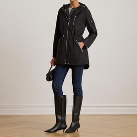 Model wearing Lauren black hooded parka coat with drawstring waist, styled with dark jeans and tall black boots.