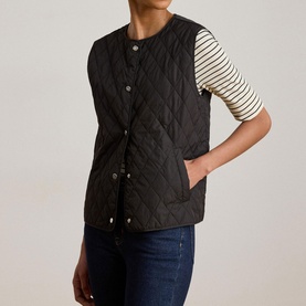 Model wearing Lauren black quilted gilet with snap buttons, styled with a striped top and dark jeans