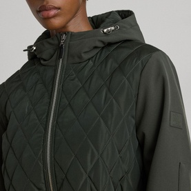 Model wearing Lauren coat in Litchfield Loden, close-up of diamond-quilted front panel, zip fastening and detachable hood with silver hardware.