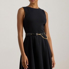 Model wearing Lauren black sleeveless dress with flared skirt, styled with a black leather belt with gold chain detail.