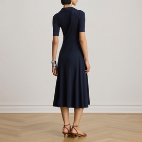 Model wearing Lauren Navy knit midi dress with short sleeves and flared skirt, styled with tan strappy heels and silver cuff bracelet.