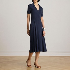 Model wearing Lauren navy midi dress with V-neckline, short sleeves and flared skirt, styled with brown strappy heels and silver bracelets.
