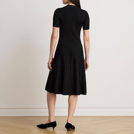 Model wearing Lauren black knit dress with short sleeves and pleated midi skirt, styled with black kitten heel mules, rear view