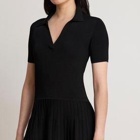 Model wearing Lauren black knit dress with V-neck polo collar, short sleeves, and pleated skirt, shown in close-up crop