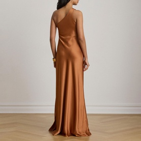 Model wearing Lauren Red Terracotta satin slip maxi dress with thin straps, low back, and floor-length bias-cut skirt, styled with a gold cuff