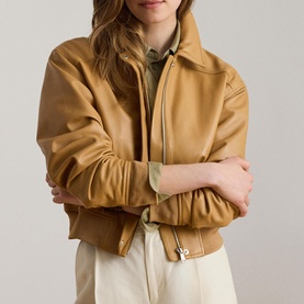 Model wearing Lauren caramel leather bomber jacket with zip fastening, styled with cream trousers and layered shirt underneath.