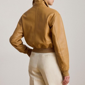 Model wearing Lauren caramel leather bomber jacket, rear view, with cream wide-leg trousers. Ribbed collar, cuffs and hem visible.
