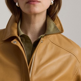 Model wearing Lauren caramel leather jacket with zip fastening and snap-button collar detail, styled over an olive shirt.