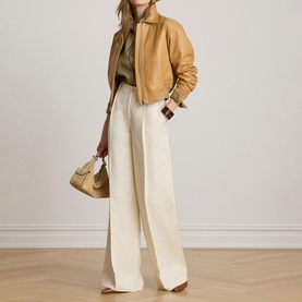 Model wearing Lauren caramel leather bomber jacket, styled with cream wide-leg trousers and tan mini bag.