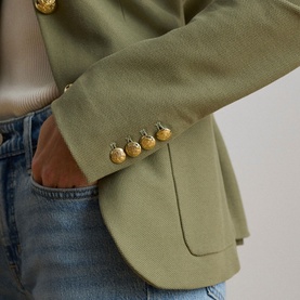 Model wearing Lauren Light Agave blazer jacket with gold embossed buttons, styled with light blue denim jeans and cream top.