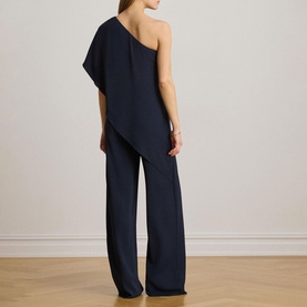 Model wearing Lauren navy one-shoulder jumpsuit with asymmetric drape top and wide-leg trousers, seen from behind