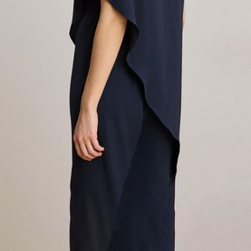 Model wearing Lauren navy jumpsuit with draped overlay detail, relaxed wide-leg silhouette, short sleeve style