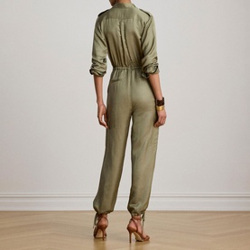 Model wearing Lauren jumpsuit in Light Agave, back view, ruched sleeves, elasticated waist, styled with gold heeled sandals