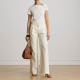 Model wearing Lauren Mascarpone Cream knit top with twist neckline detail, styled with wide-leg cream trousers, carrying tan leather bag