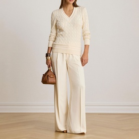 Model wearing Lauren Mascarpone Cream cable-knit V-neck sweater, styled with wide-leg cream trousers and tan leather bag.