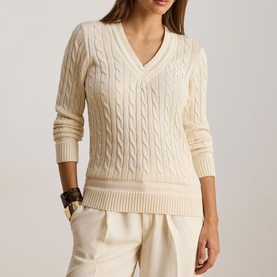 Model wearing Lauren Mascarpone Cream cable-knit V-neck jumper, styled with cream wide-leg trousers and brown bracelet.