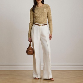 Model wearing Lauren Birch Tan cable-knit jumper with V-neck, styled with white wide-leg trousers, brown belt, and small brown handbag.