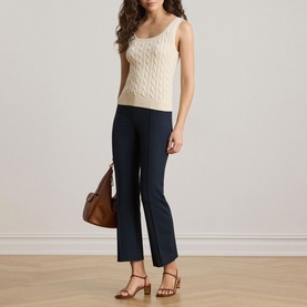 Model wearing Lauren Mascarpone Cream cable-knit sleeveless top, styled with navy flared trousers, tan heeled sandals, and brown leather bag.