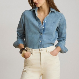 Model wearing Lauren denim shirt in Alicia Wash, styled with cream wide-leg jeans and a tan bangle bracelet.