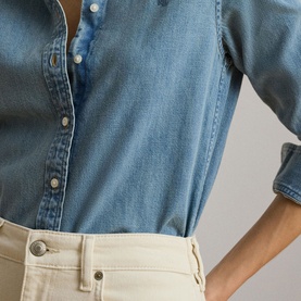 Model wearing Lauren shirt in Alicia Wash denim, close-up of torso styled with cream trousers