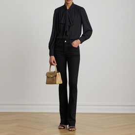 Model wearing Lauren black tie-neck long sleeve shirt with black flare jeans, styled with olive mini bag and black heeled sandals.