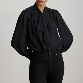 Model wearing Lauren black tie-neck blouse with balloon sleeves, styled with black jeans