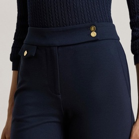 Model wearing Lauren navy trousers with gold-tone button details at waist, paired with a navy cable-knit top