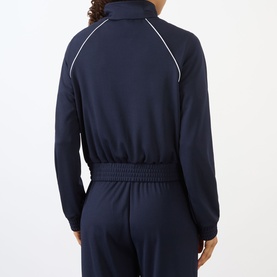 Model wearing Sporty and Rich dark navy jacket, back view, white piping trim detail, elasticated waist, styled with matching navy trousers